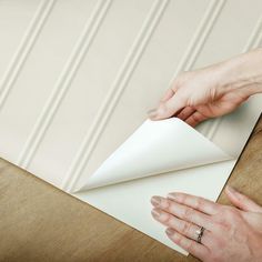 two hands are holding an envelope over a piece of paper that is folded in half