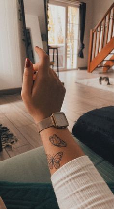 a woman's wrist with a butterfly tattoo on it