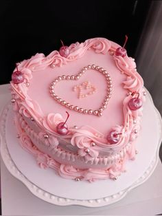 a pink heart shaped cake with pearls and cherries