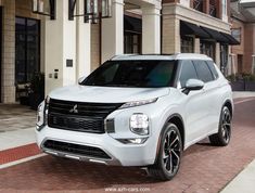 a white suv parked in front of a building on a brick sidewalk next to a street