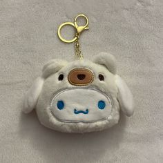 a white stuffed animal keychain with a blue eyes and nose on it's face