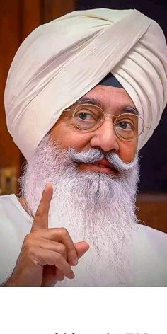 an old man with a white turban pointing at the camera and saying that he is