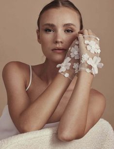 a woman with white flowers on her arm is sitting in a towel and posing for the camera