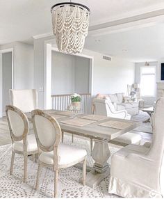 a dining room table with white chairs and a chandelier