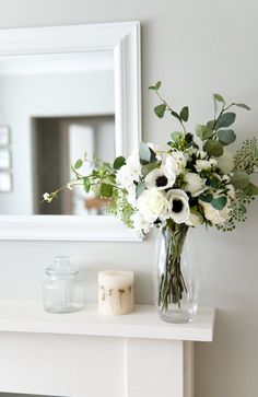 a vase filled with white flowers sitting on top of a table next to a mirror