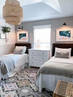 two twin beds in a bedroom with gray walls and white bedding, wicker baskets hanging from the ceiling