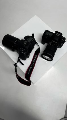 two cameras sitting on top of a white box