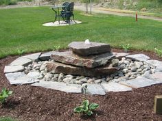 a stone fire pit in the middle of a yard