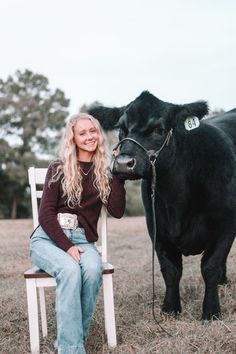 a woman sitting on a chair next to a cow