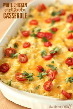 white chicken casserole with tomatoes and parsley in a dish on a wooden table