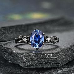 a blue stone ring sitting on top of a rock