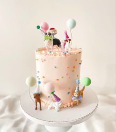 a birthday cake decorated with small figurines and balloons