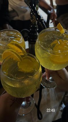 two glasses filled with yellow liquid and lemon wedges