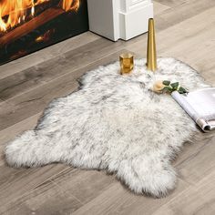 a white sheepskin rug on the floor next to a fireplace