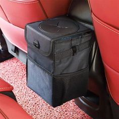 a black bag sitting on top of a red seat in the back of a car