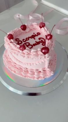 a pink birthday cake with cherries on top