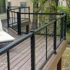 a deck with metal railings and white cushions on it's back patio area