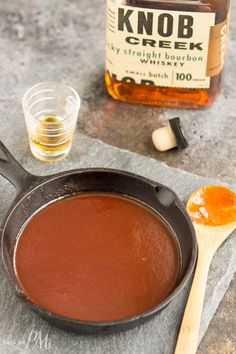 a skillet filled with liquid next to a wooden spoon and bottle of kob creek