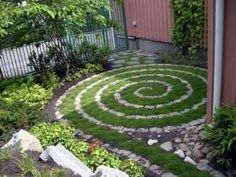 a circular garden design in the middle of a yard with rocks and grass around it