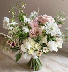 a vase filled with lots of white and pink flowers on top of a wooden table