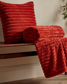 two red pillows sitting on top of a wooden bench next to a potted plant