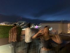 a group of people standing on top of a roof next to each other with their hands in the air