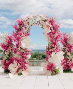 two floral archways with pink and white flowers on the ground in front of a blue sky