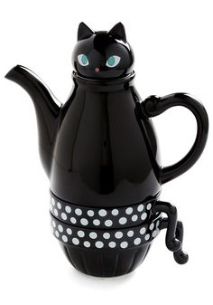 a black cat teapot with white polka dots on the bottom and a blue eyes