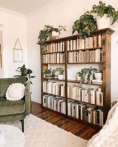 a living room filled with furniture and bookshelves covered in lots of green plants