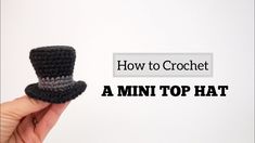 a hand holding up a small crochet top hat