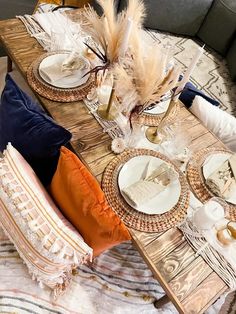 the table is set with plates, silverware and feathers on it's placemats