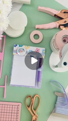 scissors, tape and other crafting supplies on a green table with pink trimmings