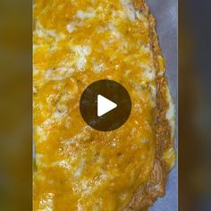 a pizza with cheese on it sitting on top of a table next to a video player