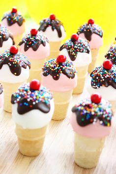 small cupcakes with frosting and sprinkles are arranged on a table