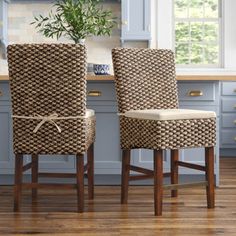 two brown chairs sitting next to each other on a wooden floor in front of blue cabinets