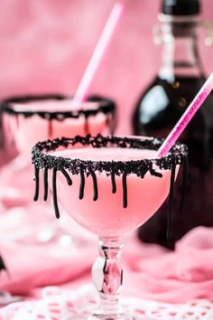 two glasses filled with pink liquid and topped with black sprinkles, sitting on a lace tablecloth