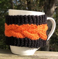 a coffee cup with an orange and black knitted handle