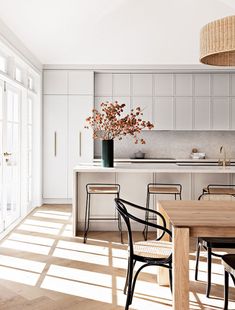 an open kitchen and dining room with white walls, wood floors and floor to ceiling windows