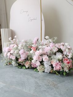 pink and white flowers are arranged in front of a sign