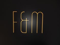 the letters bm and m are made out of gold wire on a black background