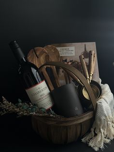 a wooden basket filled with bottles of wine and other items next to a candle holder