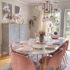 a dining room table with pink chairs and plates on it