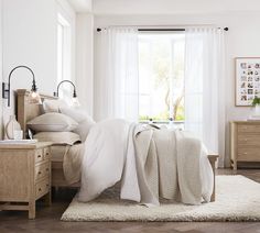 a bedroom with white walls and wooden floors has a bed, nightstands, and window