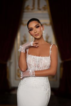 a woman in a wedding dress posing for the camera with her hand on her shoulder