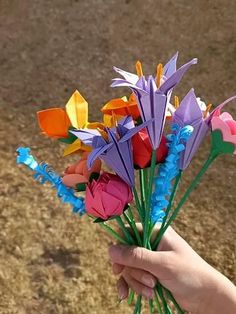 a hand holding a bunch of colorful paper flowers