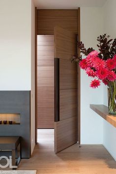 a vase filled with red flowers sitting on top of a wooden table next to a fire place