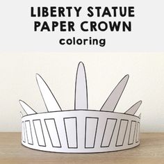 a paper crown sitting on top of a wooden table next to a white sign that says liberty statue paper crown coloring