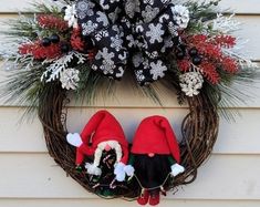 a wreath with two gnomes on it and snowflakes hanging from the front