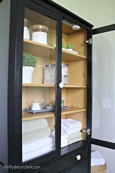 an open cabinet with towels and other items in it