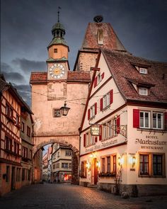 the clock tower is at the end of an old town street with cobblestone streets